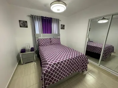 a bedroom with a bed with a purple comforter and a mirror at Joel Arturo Residences in Licey al Medio