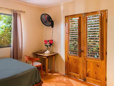 a bedroom with a bed and a table and a window at La Hacienda Hostel-Rancho in Las Galeras