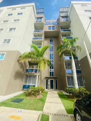 a large building with palm trees in front of it at Confortable y lujoso apartamento en santiago in Santiago de los Caballeros
