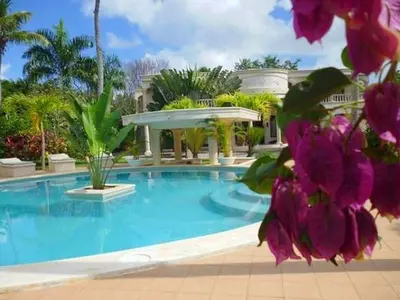 a swimming pool with purple flowers in front of a building at Villa La Plantacion in Las Galeras