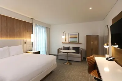 a hotel room with a bed and a chair and a table at Courtyard by Marriott Santo Domingo Piantini in Santo Domingo