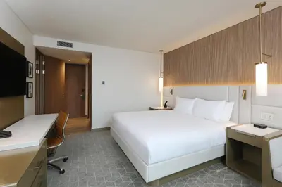 a hotel room with a large white bed and a desk at Courtyard by Marriott Santo Domingo Piantini in Santo Domingo