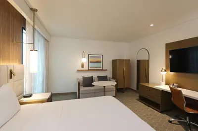 a hotel room with a large white bed and a desk at Courtyard by Marriott Santo Domingo Piantini in Santo Domingo