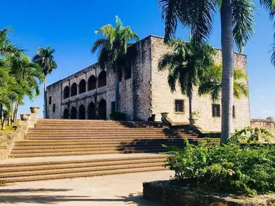 a building with stairs and palm trees in front at Hostal María Fernanda in Santo Domingo
