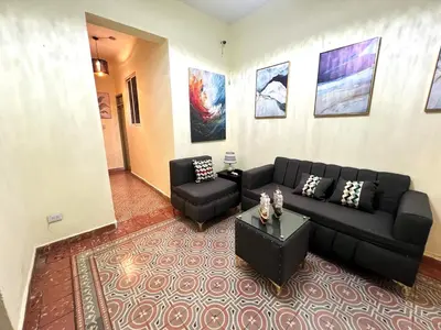 a living room with a black couch and a table at Hostal María Fernanda in Santo Domingo