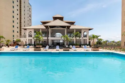 a large swimming pool with chairs and a building at 3 BDR Ocean View luxury Apartment . Sleeps 6 in Santo Domingo