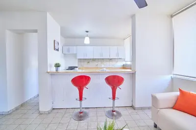 a kitchen with two red stools in front of a counter at Rentamos Aparta Estudio for short or long stay in Santo Domingo