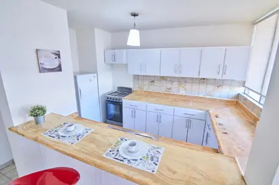 a kitchen with white cabinets and a wooden counter top at Rentamos Aparta Estudio for short or long stay in Santo Domingo
