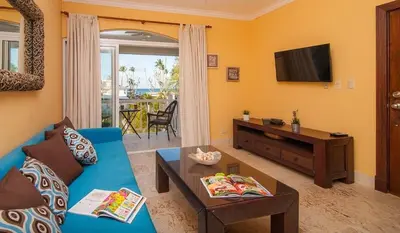 a living room with a blue couch and a tv at A pasos de la playa cerca de bares y restaurantes in Punta Cana