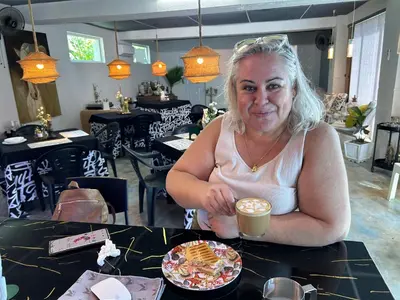 a woman sitting at a table with a cup of coffee at VILLA GRANDEZZA in Punta Cana
