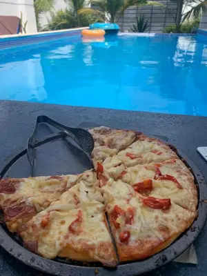 a pizza sitting on a table next to a swimming pool at VILLA GRANDEZZA in Punta Cana