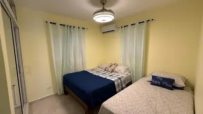 a small bedroom with two beds and a light at Our Cozy Home, Wi-Fi, AC, Parking, Near Beaches and Attractions in quiet area in Nagua