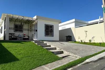 a house with a grassy yard in front of it at Our Cozy Home, Wi-Fi, AC, Parking, Near Beaches and Attractions in quiet area in Nagua