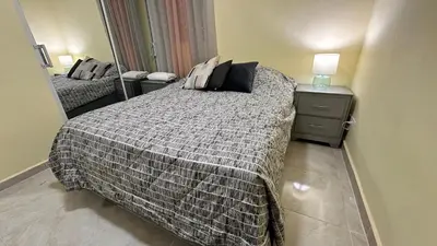 a small bedroom with a bed and a mirror at Our Cozy Home, Wi-Fi, AC, Parking, Near Beaches and Attractions in quiet area in Nagua