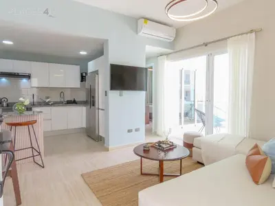 a living room with a white couch and a table at Cerca de la playa y restaurantes espacio relajante in Punta Cana