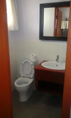 a bathroom with a toilet and a sink and a mirror at Residencial Las Palmeras de Willy Boca Chica in Boca Chica