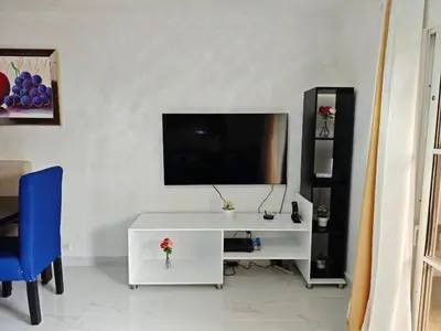 a living room with a tv and a white cabinet at Residencial Las Palmeras de Willy Boca Chica in Boca Chica