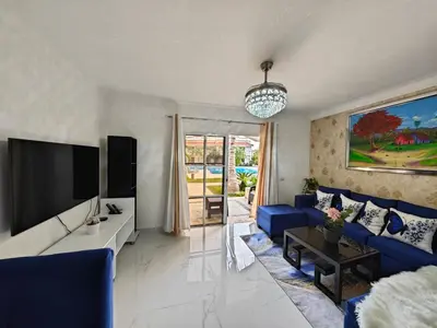 a living room with a blue couch and a tv at Residencial Las Palmeras de Willy Boca Chica in Boca Chica