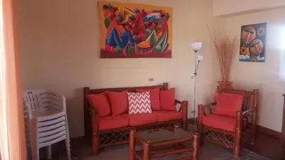 a living room with two red chairs and a painting at Residencial Las Palmeras de Willy Boca Chica in Boca Chica