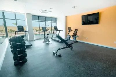a gym with a row of exercise bikes and a flat screen tv at Wyndham Garden El Morro Montecristi in El Rincón