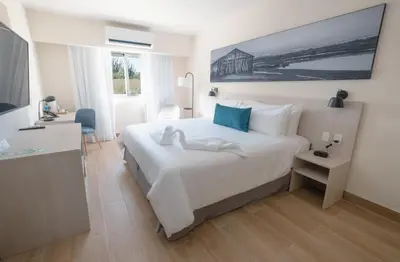 a bedroom with a large white bed and a desk at Wyndham Garden El Morro Montecristi in El Rincón
