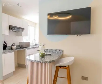 a kitchen with a counter with a tv on the wall at Hermoso apartamento 1 hab a pasos de la playa in Punta Cana