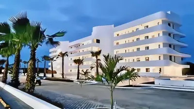 a large white building with palm trees in front of it at Ph in Cana Rock Star With Golf View And Pool in Punta Cana
