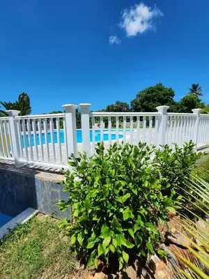 a white fence with a bush next to a pool at Bella Villa room with large pool and close to beach in Las Galeras