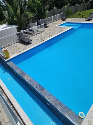 a blue swimming pool with chairs around it at Bella Villa room with large pool and close to beach in Las Galeras
