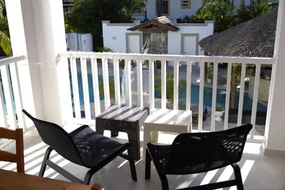 a table and chairs on a balcony with a pool at Tamarindo Dominicus by Mireya in La Laguna