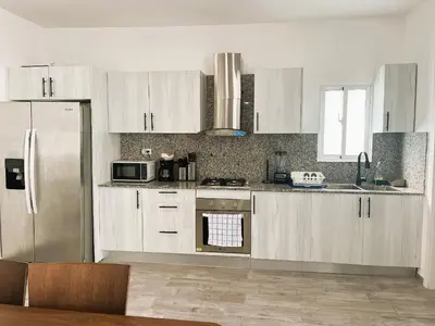 a kitchen with white cabinets and a stainless steel refrigerator at Arena Village | 2H Retiro con Vista a Piscina in Punta Cana
