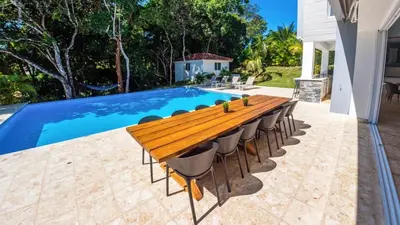a wooden table and chairs next to a swimming pool at Villa Collie Luxury Retreat7 King Master BRMaid in Sosúa