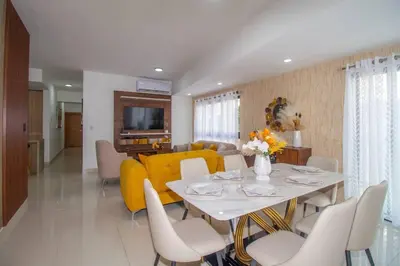 a dining room and living room with a table and yellow couch at Brand New Luxury Home in Santo Domingo