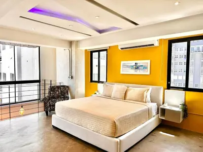 a bedroom with a bed with yellow walls and windows at New Loft Apt Full AC King Bed in Santo Domingo
