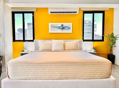 a bedroom with a large bed with an orange wall at New Loft Apt Full AC King Bed in Santo Domingo
