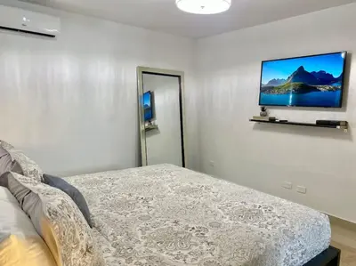 a bedroom with a bed and a flat screen tv on the wall at Stylish Apt Full AC King Bed in Los Prados