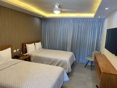 a hotel room with two beds and a television at New Garden Hotel in Sosúa