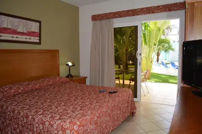 a bedroom with a bed and a door to a patio at New Garden Hotel in Sosúa