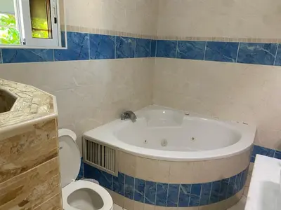 a bathroom with a bath tub and a toilet at New Garden Hotel in Sosúa