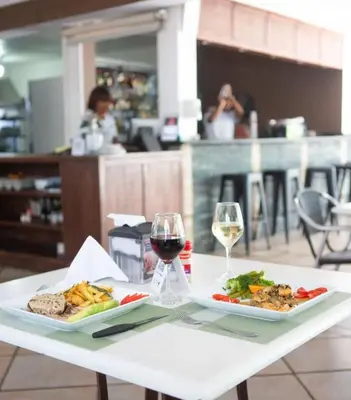 a table with two plates of food and a glass of wine at New Garden Hotel in Sosúa