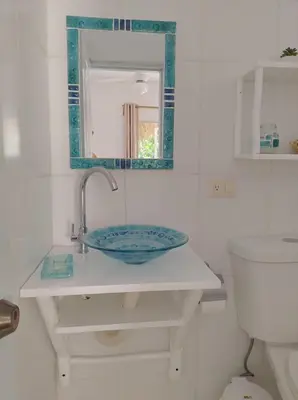 a bathroom with a sink and a mirror and a toilet at Quédate Aquí in Las Galeras
