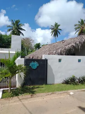 a white building with a thatched roof at Quédate Aquí in Las Galeras