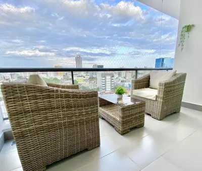a balcony with wicker chairs and a table and a large window at Lovely City Center Condo in Los Prados