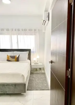 a white bedroom with a bed and a window at Lovely City Center Condo in Los Prados