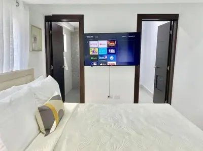 a bedroom with a bed with a tv on the wall at Lovely City Center Condo in Los Prados
