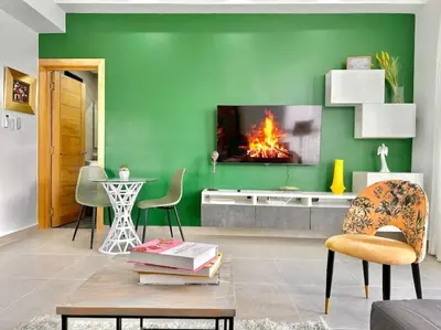 a living room with a green wall with a fireplace at Stunning City Center Condo in Los Prados