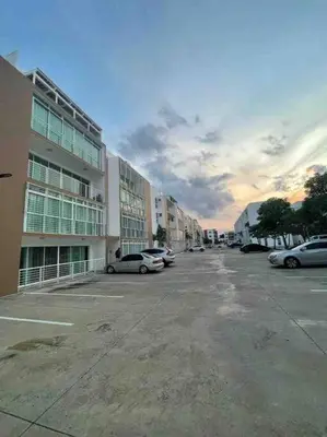 a parking lot with cars parked in front of a building at Hermoso conjunto residencial con piscina in Santiago de los Caballeros