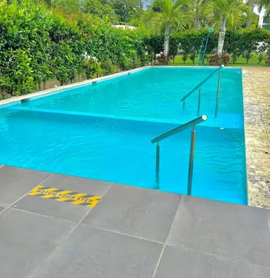a large blue swimming pool with a metal hand rail at Hermoso conjunto residencial con piscina in Santiago de los Caballeros