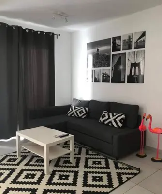 a living room with a black couch and a table at Estrella Dominicus con hermosa piscina! 1st floor in La Laguna