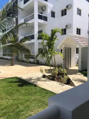 a white building with palm trees in front of it at Sol Caribe 101 Bayahibe con linda piscina! in Bayahibe